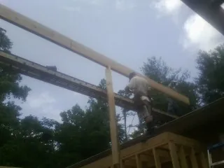 Carpenter setting a ridge beam over a new addition frame — Ice Dam Removal by Roofing Brothers in Pewamo