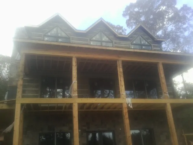Dormers and porch framing on a large log home under construction — Roof Coating work by our crew in Pewamo