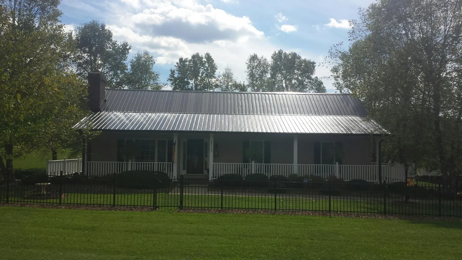 Gray metal roof on a brick ranch with a full width front porch — Gutter Guard Installation work by our crew in Pewamo