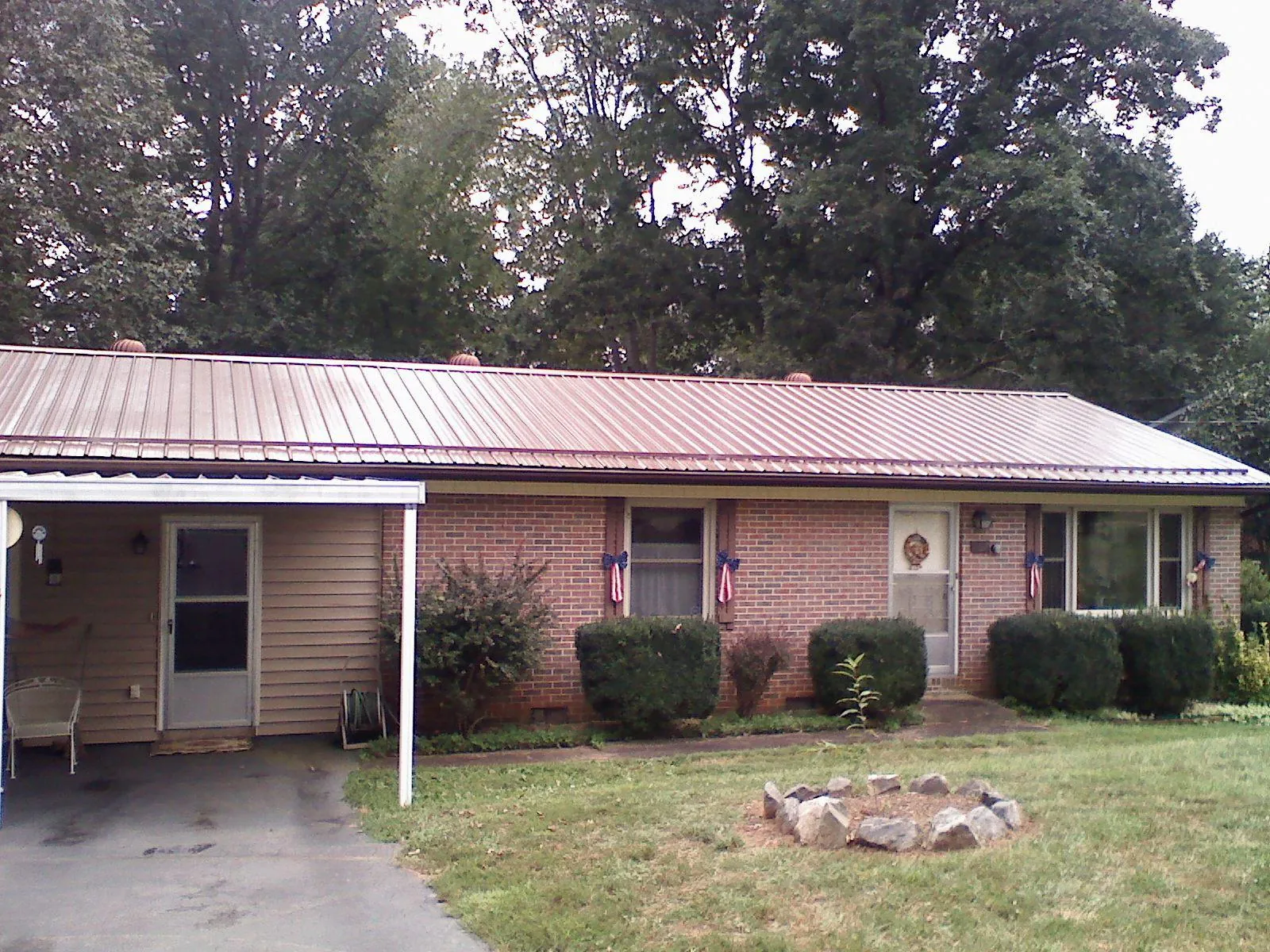 Bronze metal roof and carport on a brick ranch home — Roof Repair work by our crew in Pewamo