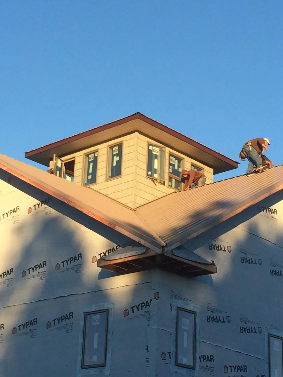 Roofers working around a rooftop cupola on a new metal roof at sunset — Roof Waterproofing in Pewamo by Roofing Brothers